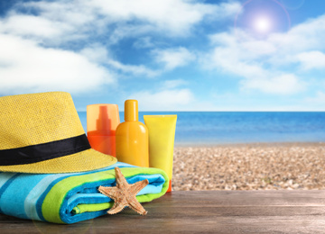 Beach objects on wooden table near sea, space for text. Summer vacation 