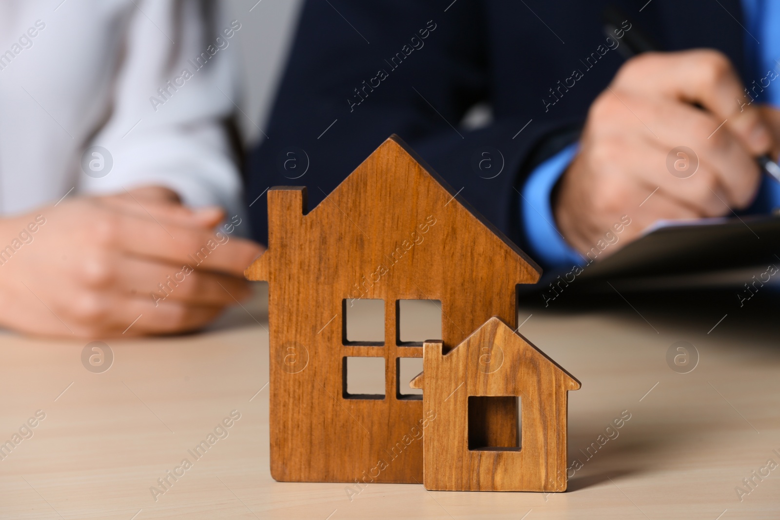 Photo of Real estate agent working with client at table, focus on house figures. Home insurance