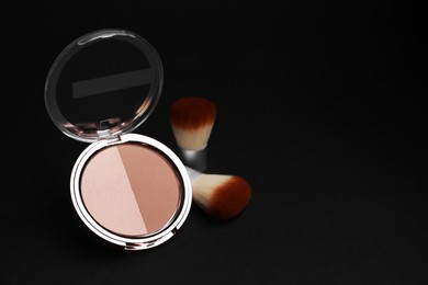 Photo of Open face powder and makeup brushes on black background, space for text