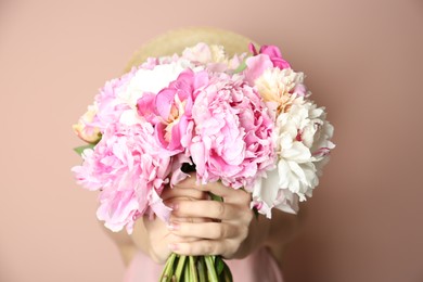 Photo of Woman with bouquet of beautiful peonies on beige background, closeup