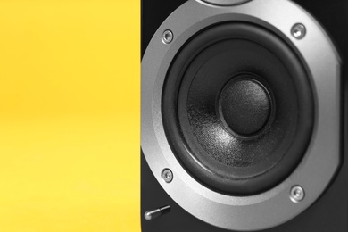 Modern powerful audio speaker on yellow background, closeup