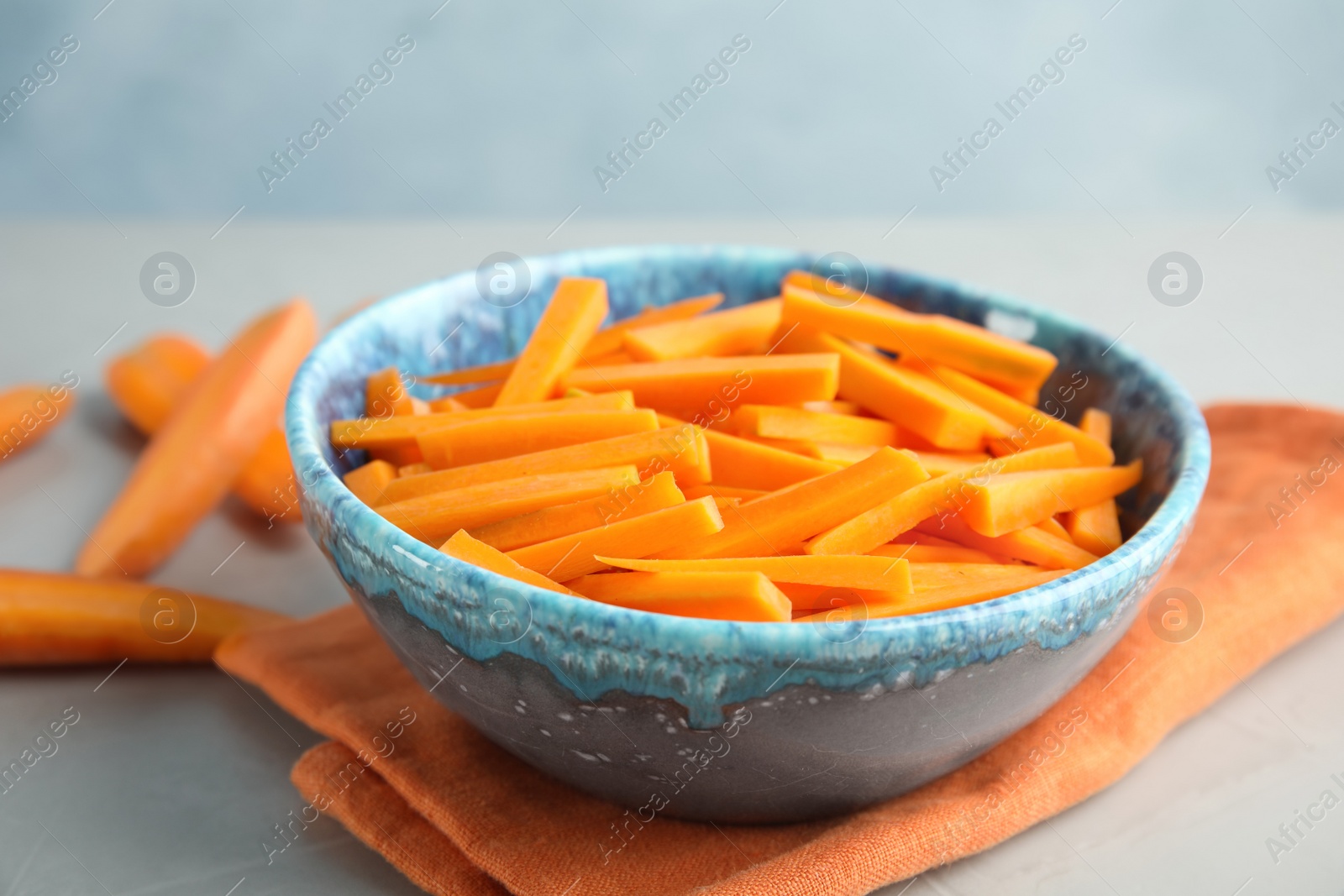 Photo of Bowl with cut ripe carrot on table