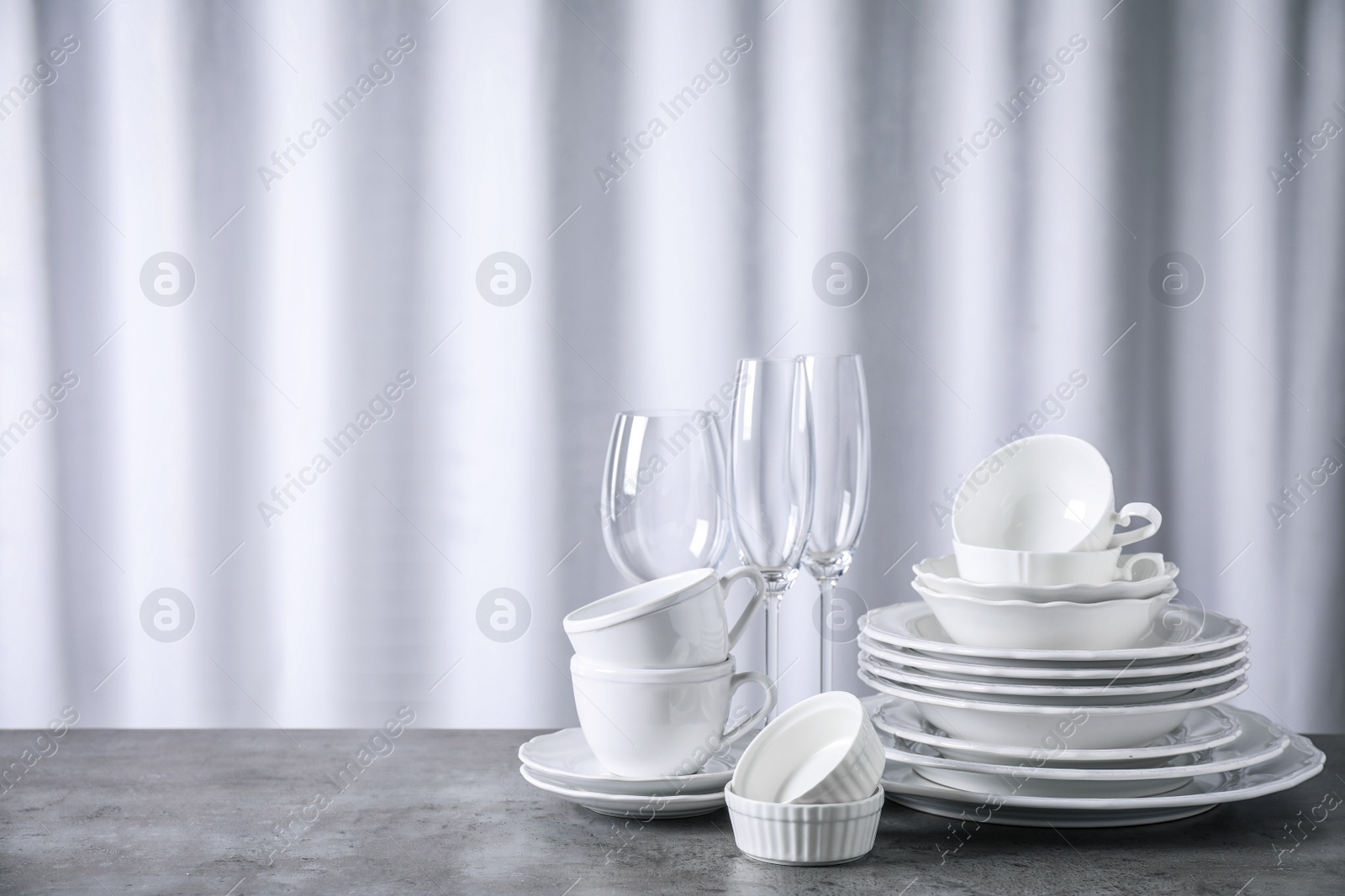 Photo of Set of clean dishware on grey table