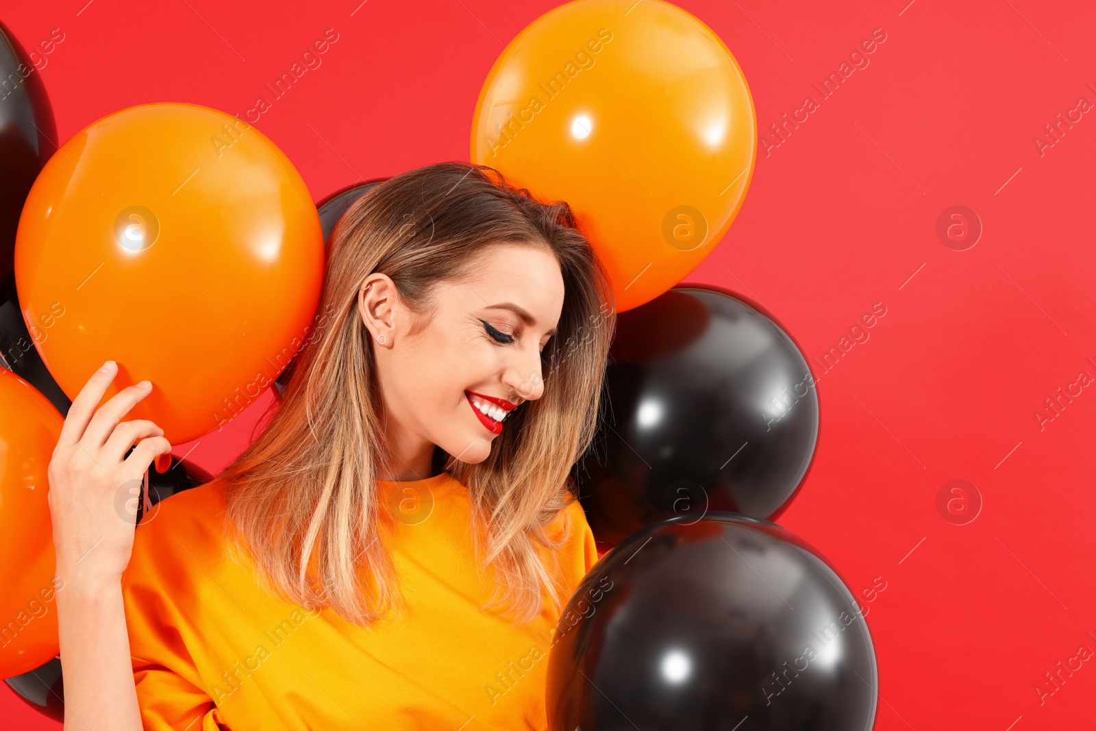 Photo of Beautiful woman with balloons on red background. Halloween party