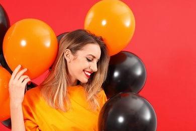 Photo of Beautiful woman with balloons on red background. Halloween party