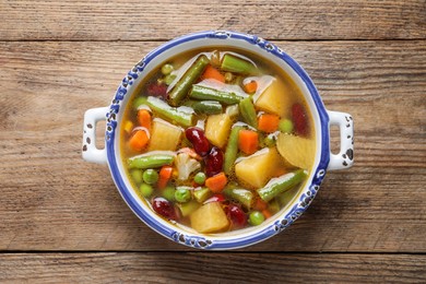 Photo of Bowl of tasty turnip soup on wooden table, top view