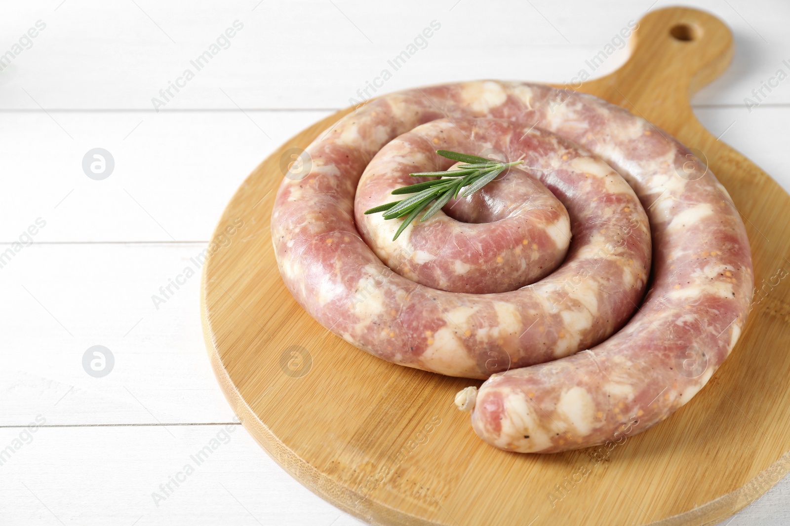 Photo of Raw homemade sausage and rosemary on white wooden table, closeup. Space for text