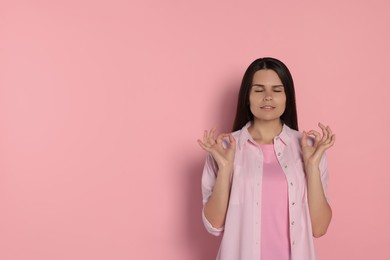 Photo of Young woman meditating on pink background, space for text. Zen concept