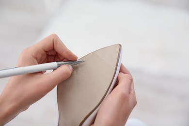 Young bride writing on her shoe indoors, closeup. Wedding superstition