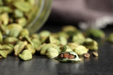 Dry cardamom pods on dark grey table, closeup