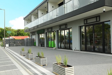 City street with modern store and potted green plants