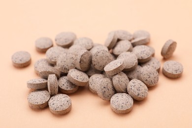 Photo of Pile of beer yeast pills on pale orange background, closeup