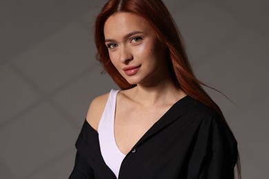 Photo of Beautiful young woman in black shirt on gray background