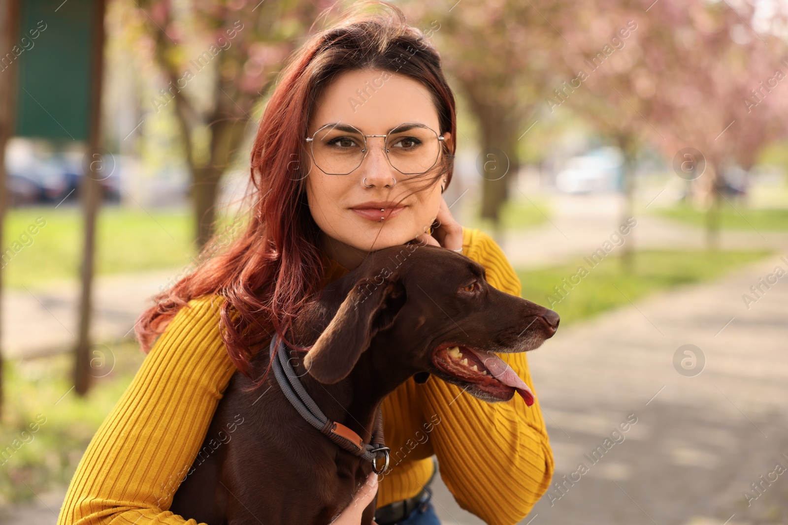 Photo of Woman with her cute German Shorthaired Pointer dog in park on spring day