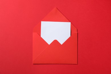 Photo of Letter envelope with card on red background, top view