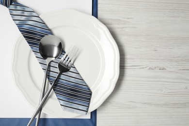Photo of Plate with cutlery, tie and clipboard on wooden table, top view and space for text. Business lunch concept