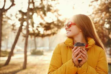 Photo of Young woman with cup of coffee in morning outdoors