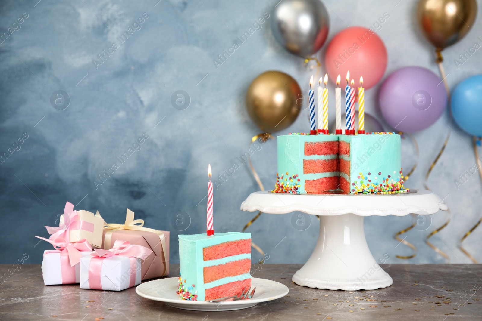 Photo of Fresh delicious cake with candles and gifts on table against color background