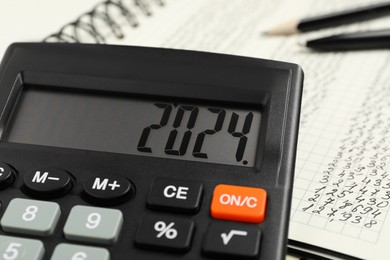 Photo of Calculator and notebook with data on table, closeup view