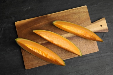 Slices of tasty fresh melon on black slate table, top view