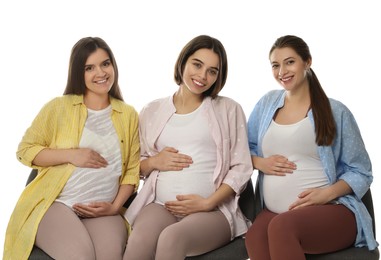 Happy pregnant women sitting on chairs against white background