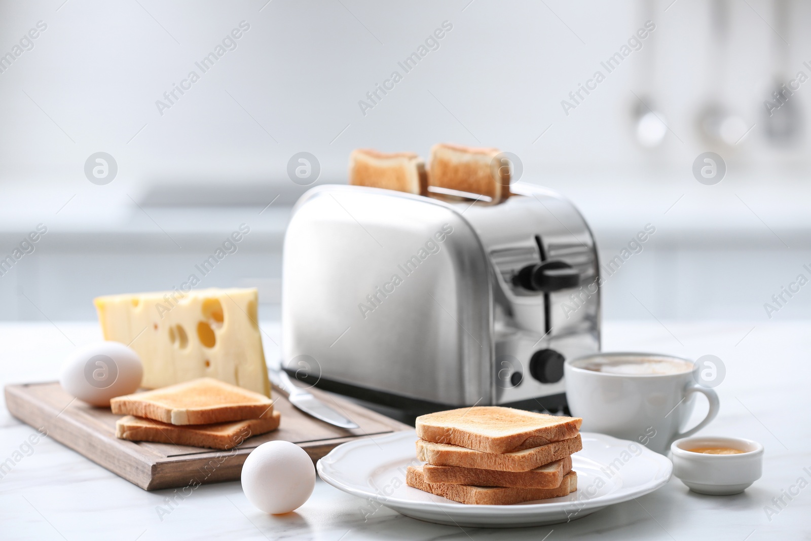 Photo of Modern toaster and tasty breakfast on white marble table in kitchen