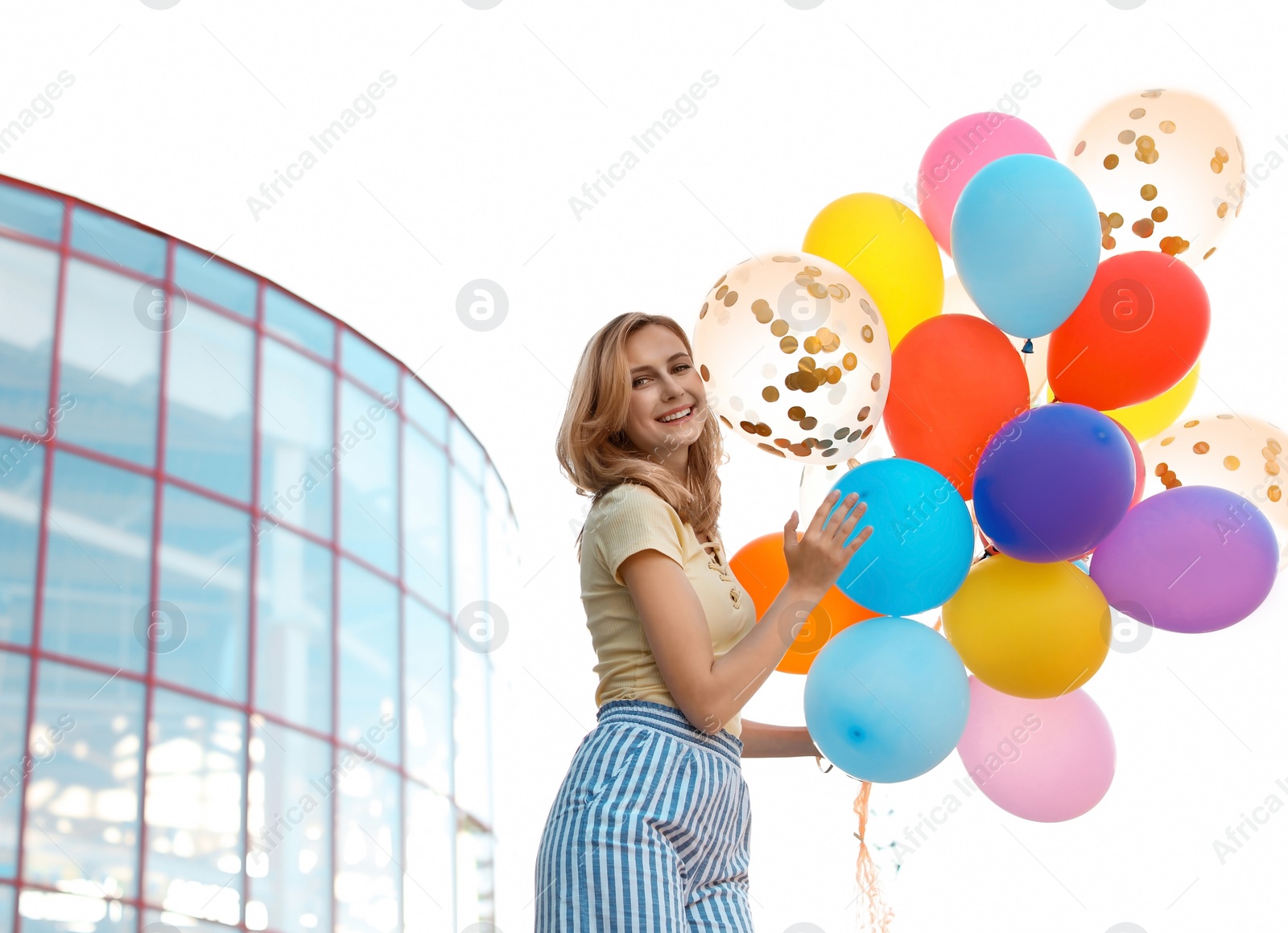 Photo of Young woman with colorful balloons outdoors on sunny day