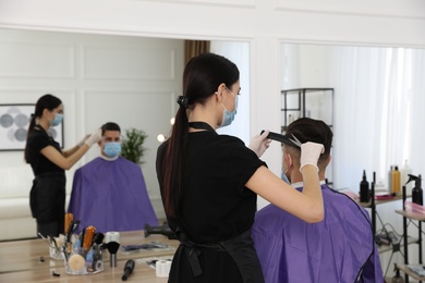 Professional stylist working with client in salon. Hairdressing services during Coronavirus quarantine