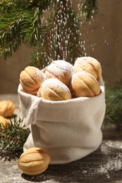 Photo of Sprinkling powdered sugar onto delicious nut shaped cookies on wooden table