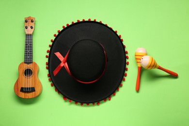 Photo of Mexican sombrero hat, maracas and guitar on green background, flat lay