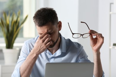 Man with glasses suffering from eyestrain in office