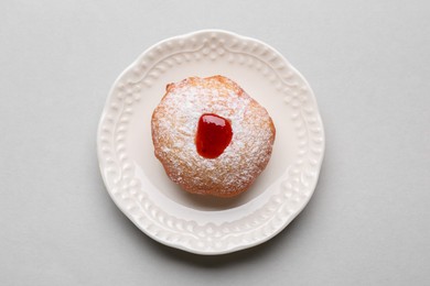 Photo of Hanukkah donut with jelly and powdered sugar on light grey background, top view