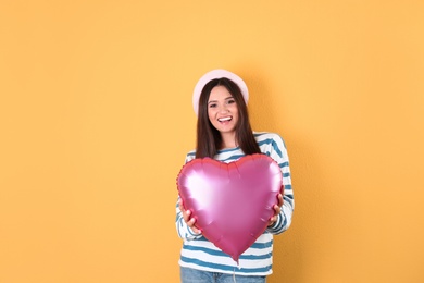 Photo of Portrait of young woman with heart shaped balloon on color background. Space for text