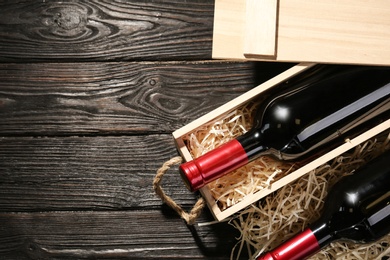 Photo of Crate and bottles of wine on wooden table, flat lay. Space for text