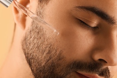 Man applying cosmetic serum onto face, closeup