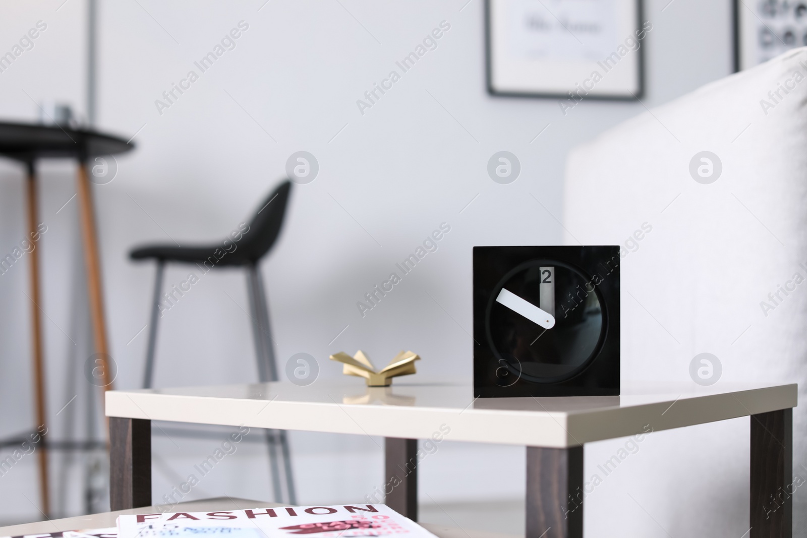 Photo of Analog alarm clock on table in living room. Time of day