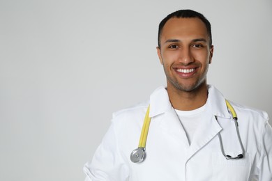 Photo of Doctor or medical assistant (male nurse) in uniform with stethoscope on light grey background. Space for text