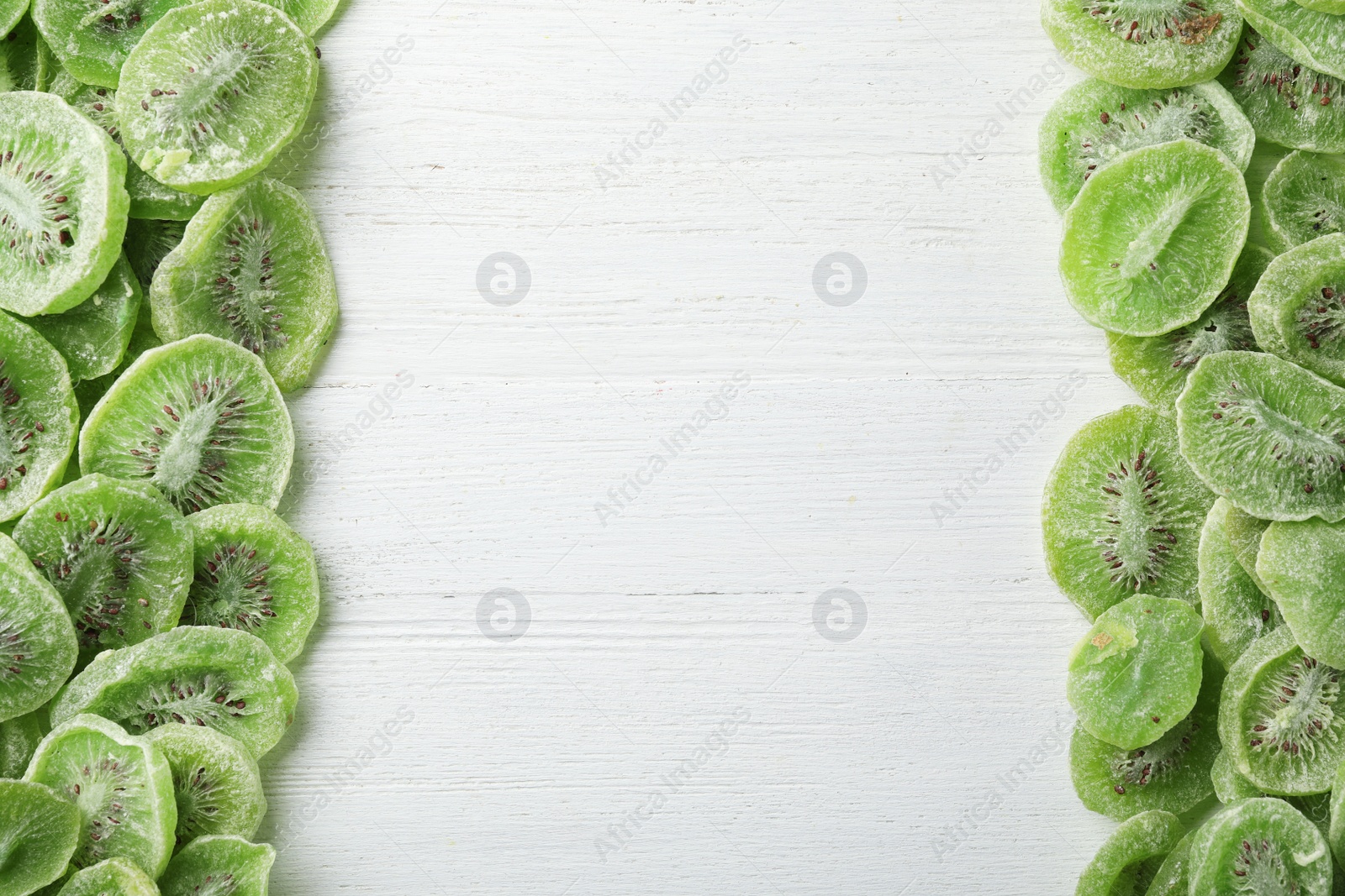 Photo of Frame made of kiwi on wooden background, top view with space for text. Dried fruit as healthy food