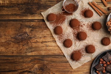 Photo of Delicious chocolate truffles and ingredients on wooden table, flat lay. Space for text