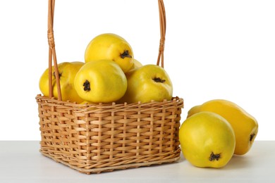 Basket with delicious fresh ripe quinces on light wooden table against white background