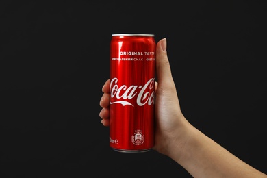 MYKOLAIV, UKRAINE - NOVEMBER 14, 2018: Woman holding Coca-Cola can on black background