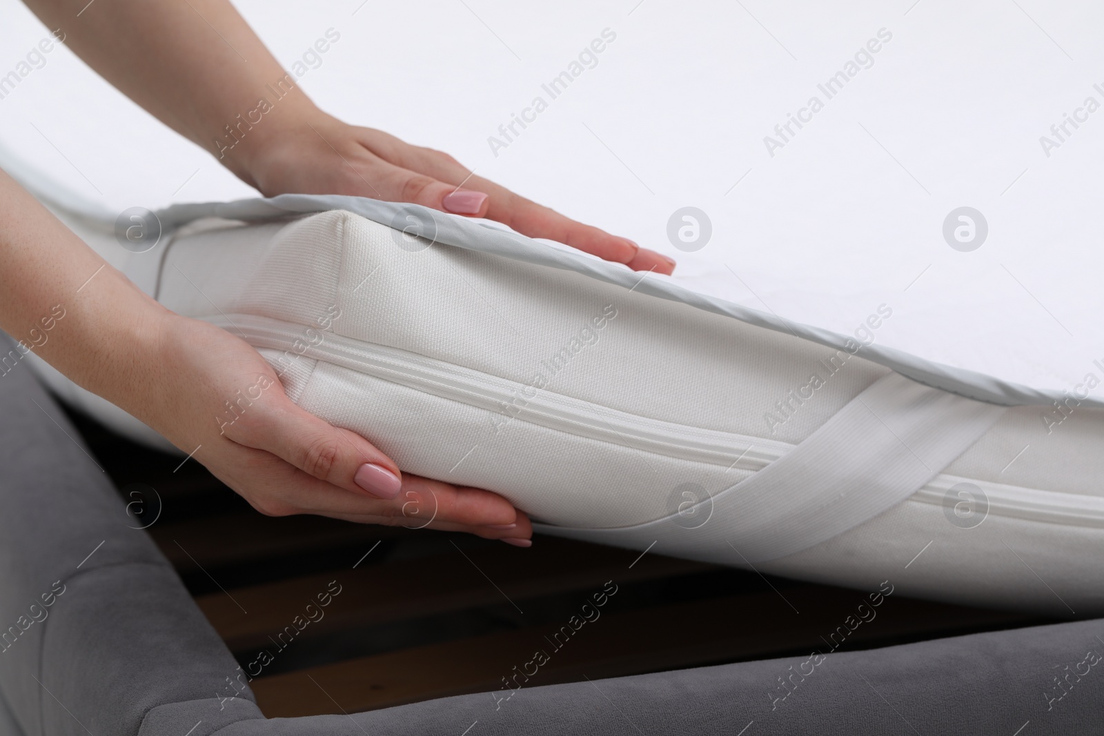 Photo of Woman putting new soft mattress on bed, closeup