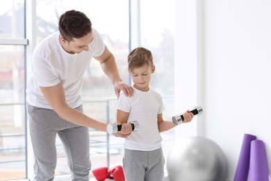 Dad and his son training with dumbbells in gym