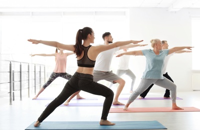 Photo of Group of people in sportswear practicing yoga indoors