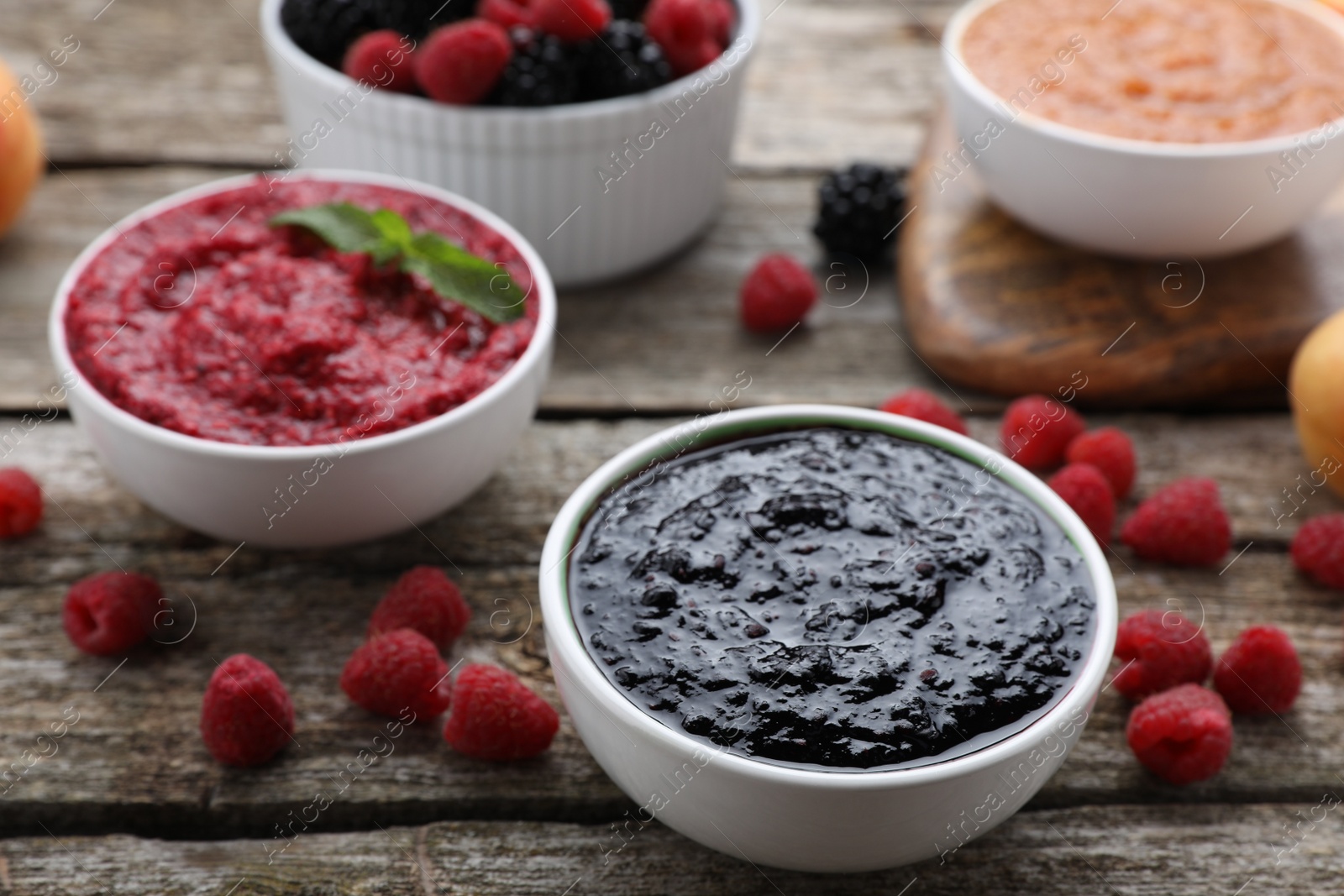 Photo of Different puree in bowls and fresh fruits on wooden table