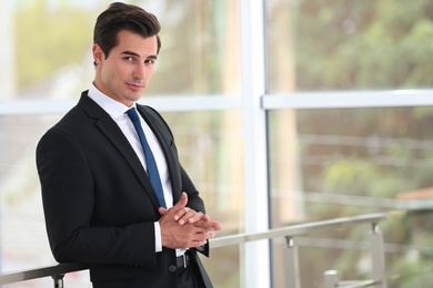 Handsome young man in stylish suit indoors. Space for text