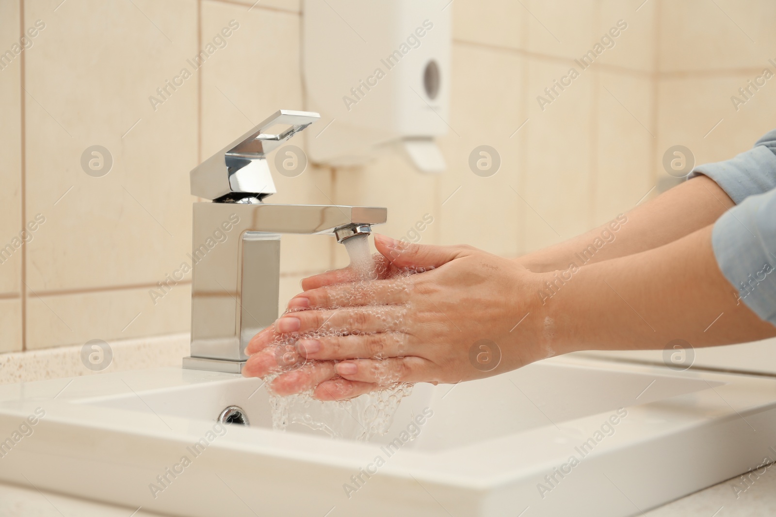 Photo of Woman washing hands with antiseptic soap in bathroom, closeup. Virus prevention