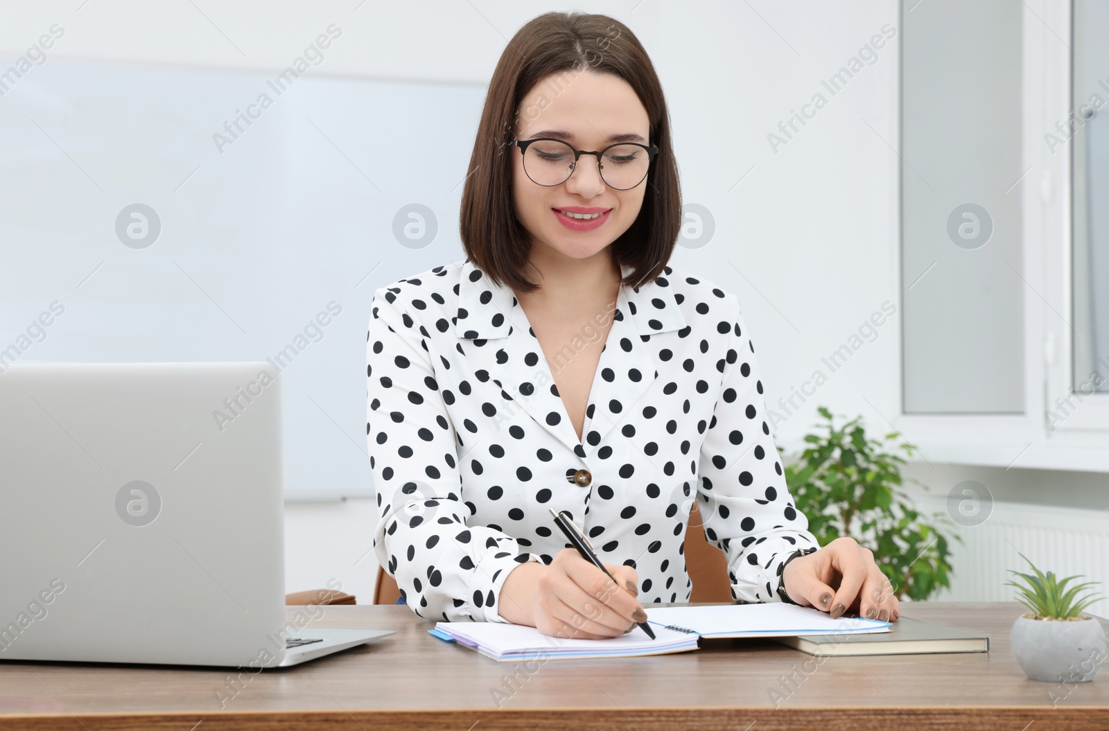 Photo of Happy young intern working at table in modern office