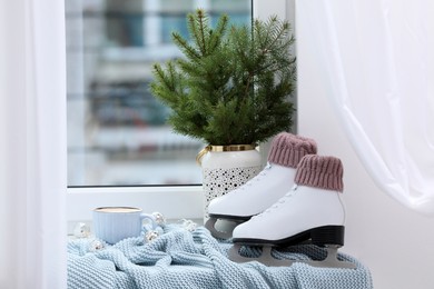 Pair of ice skates and Christmas decor near window indoors