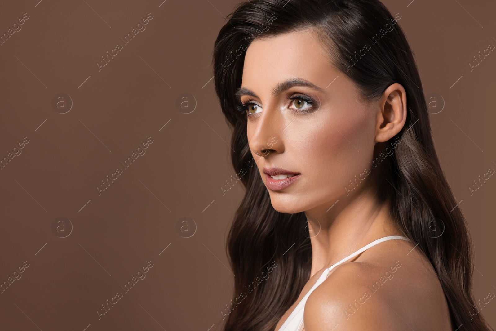 Photo of Hair styling. Beautiful woman with wavy long hair on brown background. Space for text